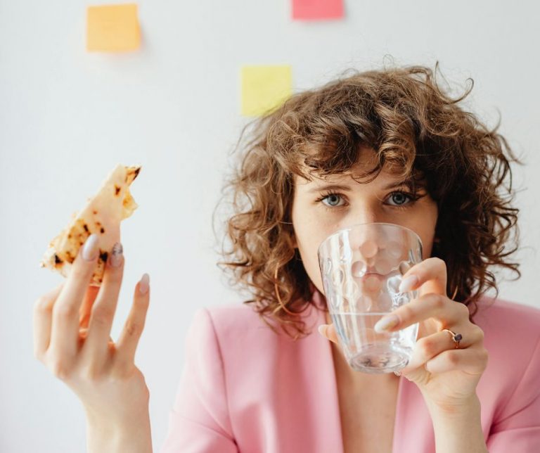 Frau im stressigen Alltag mit Kaffee und Pizza in der Hand